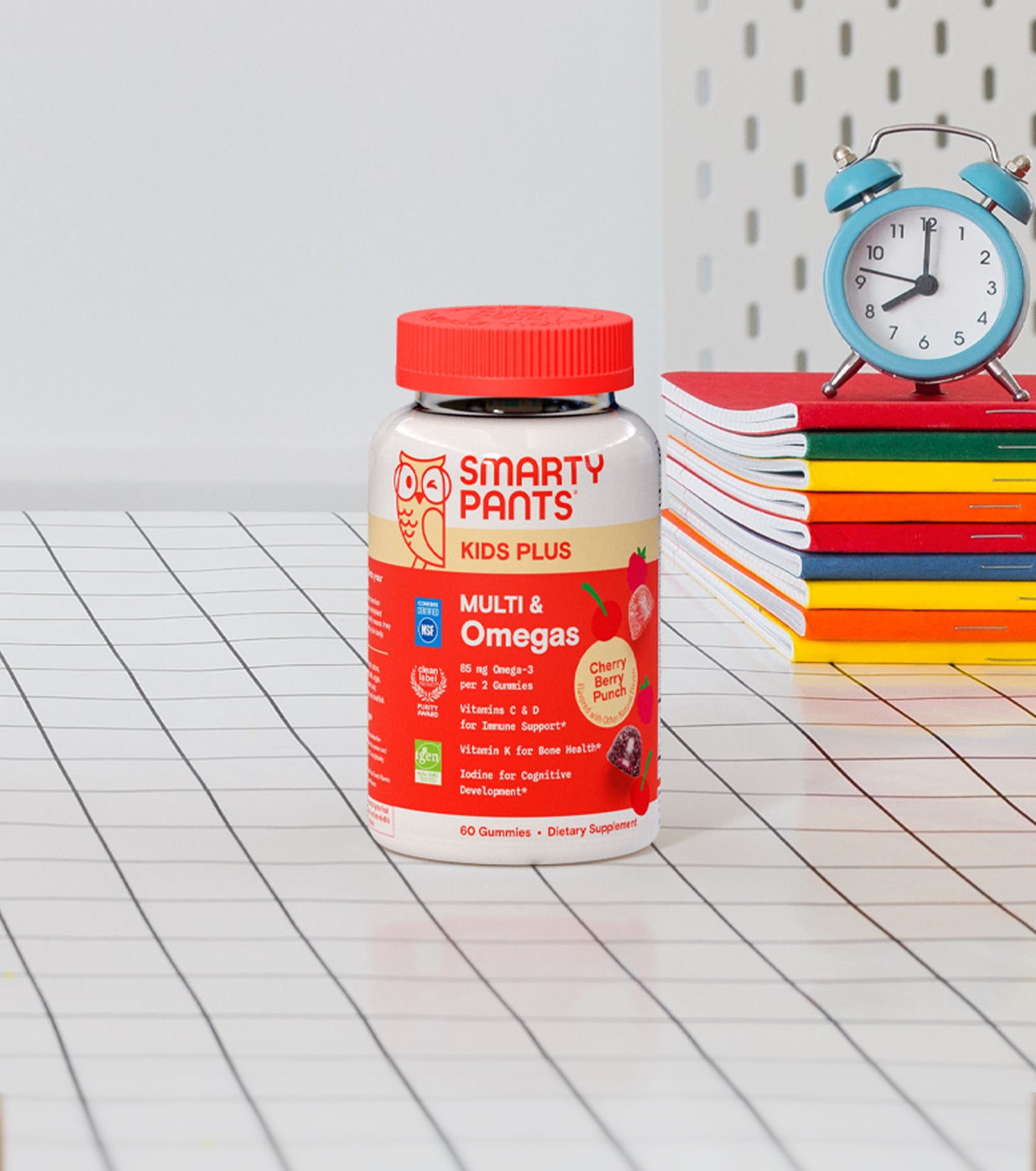 Kids Plus Multi & Omegas Cherry Berry Punch on graph paper with books and a small clock