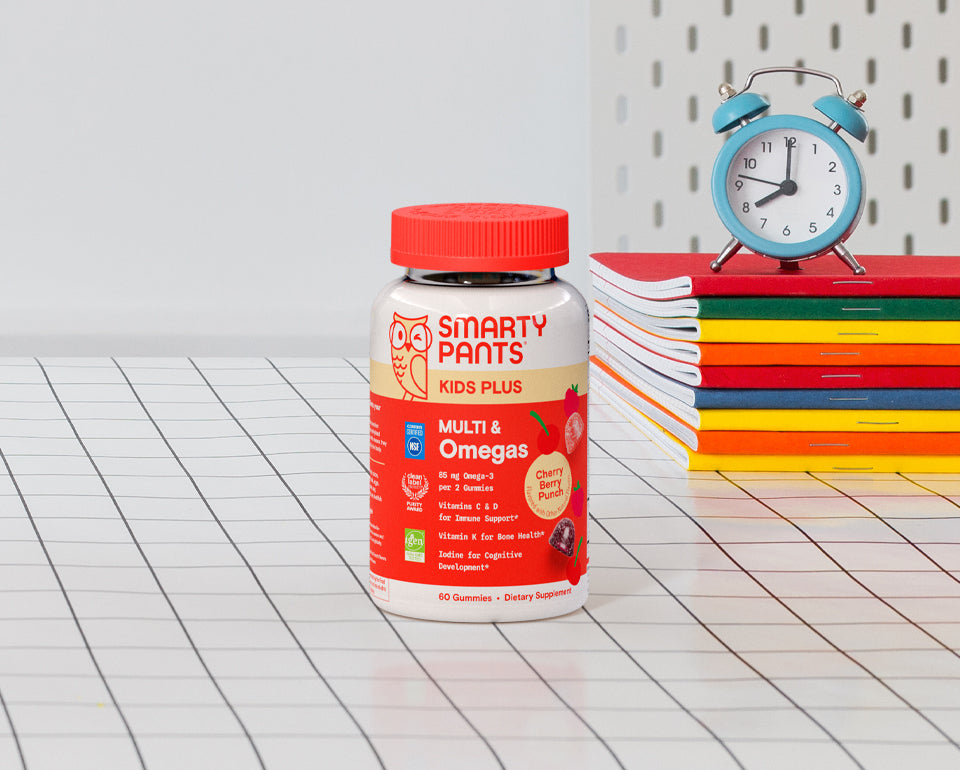 Kids Plus Multi & Omegas Cherry Berry Punch on graph paper with books and a small clock