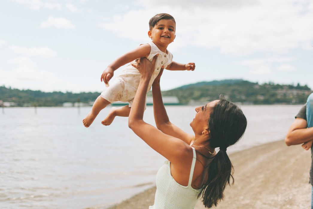 Mom holding her baby son up in the air on the beach