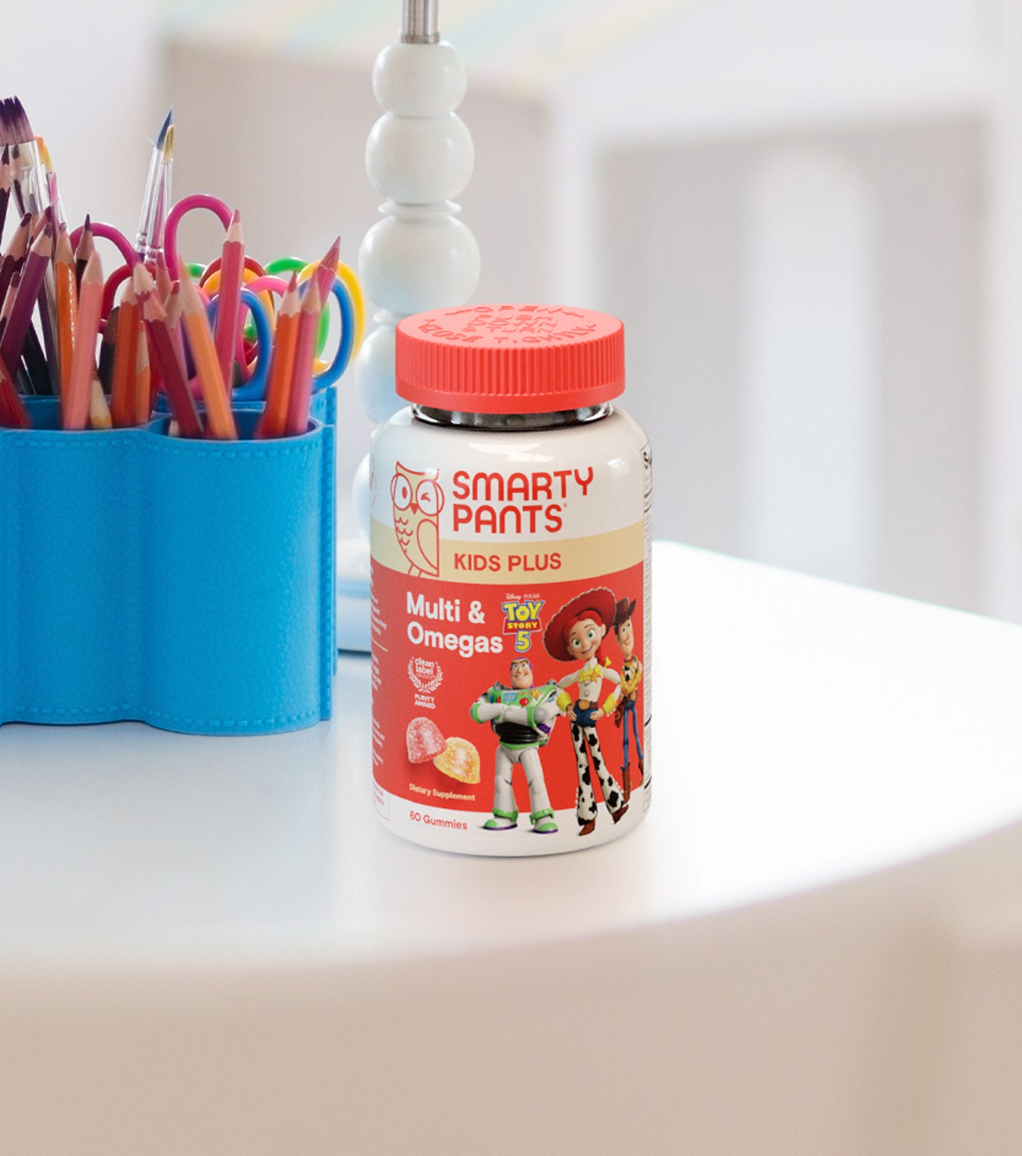 Smarty Pants Toy Story 5 Kids Plus Multi & Omegas bottle on a table with colorful pencils in the background