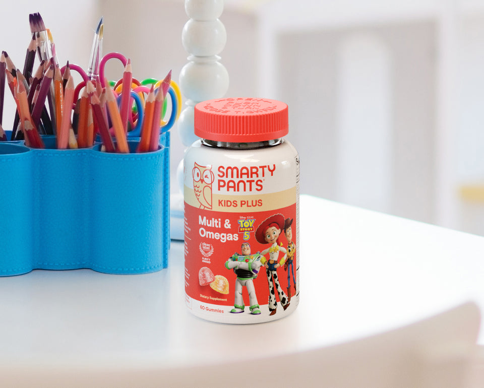 Smarty Pants Toy Story 5 Kids Plus Multi & Omegas bottle on a table with colorful pencils in the background