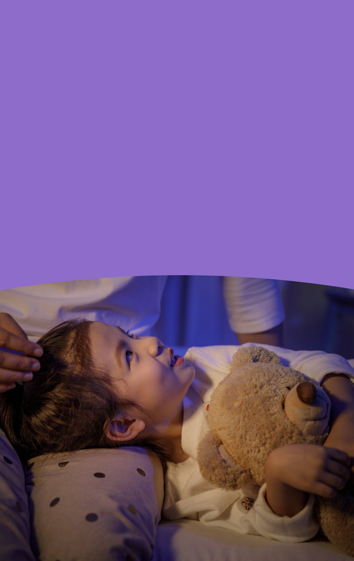 Child lying in bed with a teddy bear