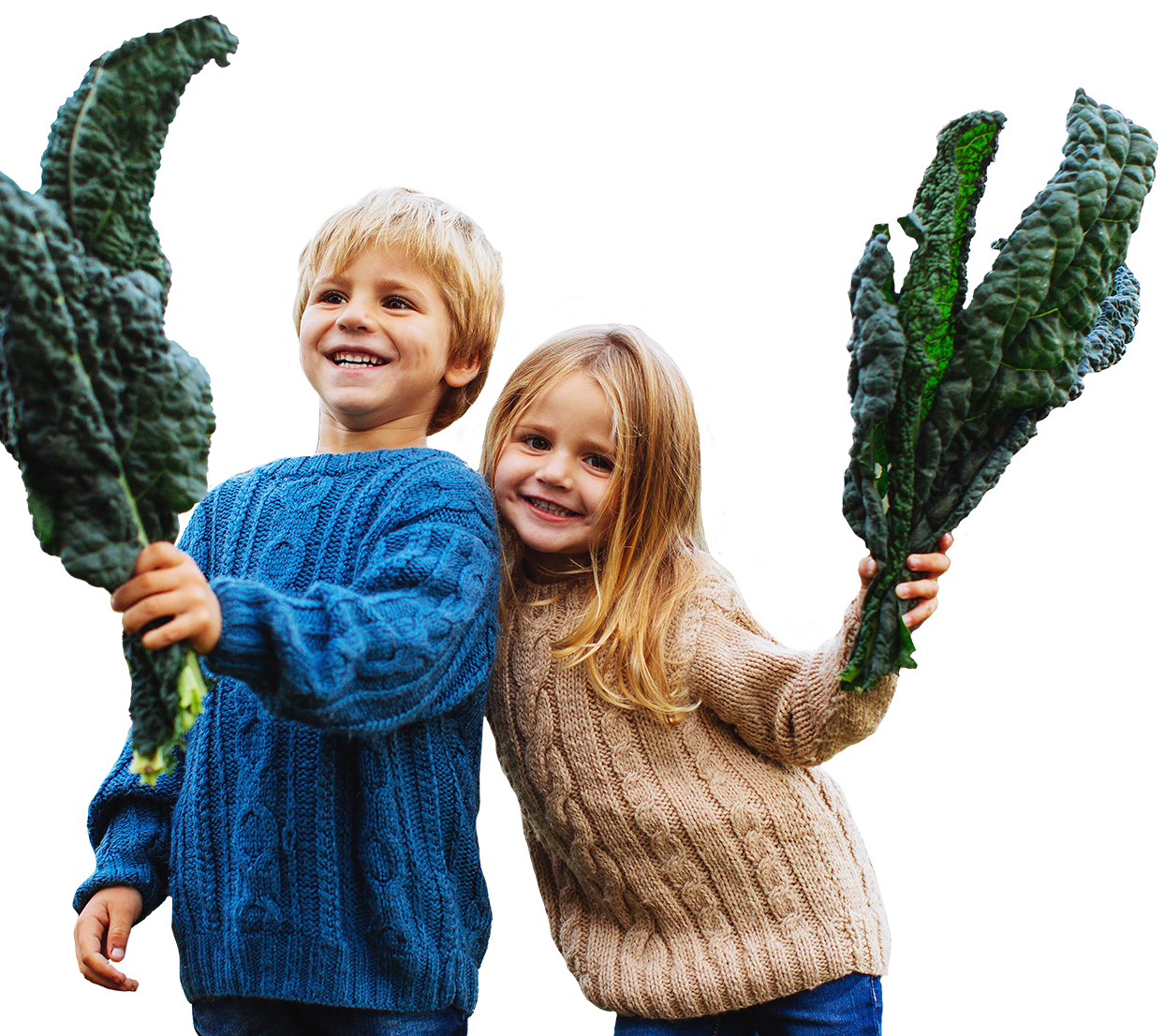 two smiling kids holding kale leaves