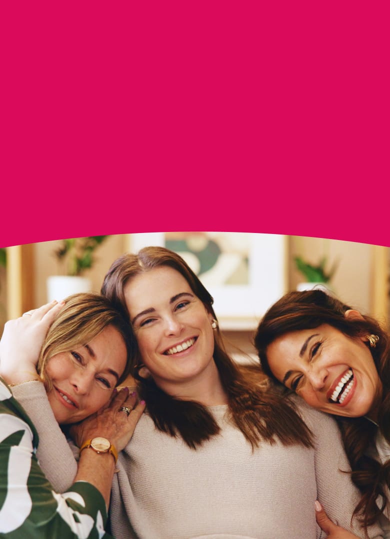 Two women hugging with a pink background and two gummies.