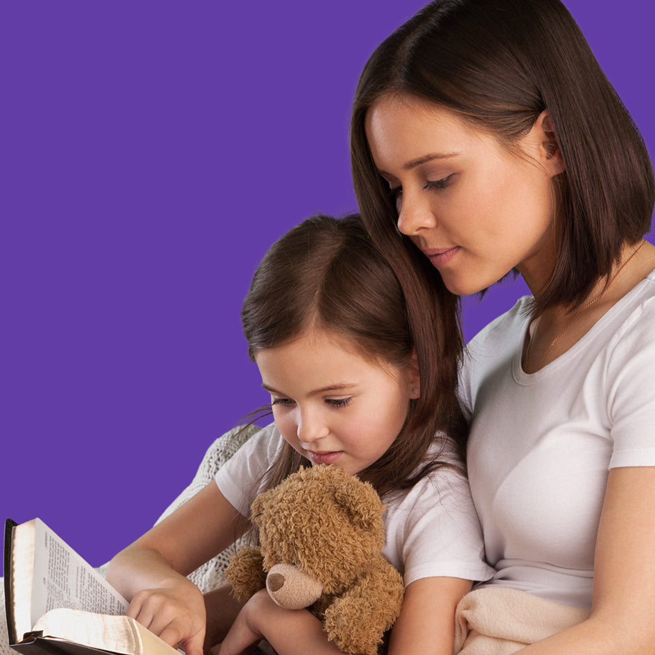 Woman and young girl reading a book together with a teddy bear on a purple background